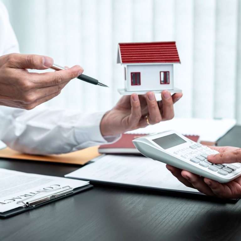 Hands reviewing a model home and calculator